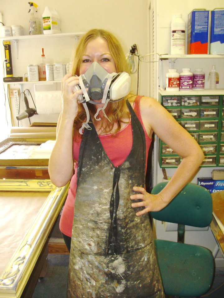 Kate displaying some of the tools of her trade: a respirator and a well-worn smock.